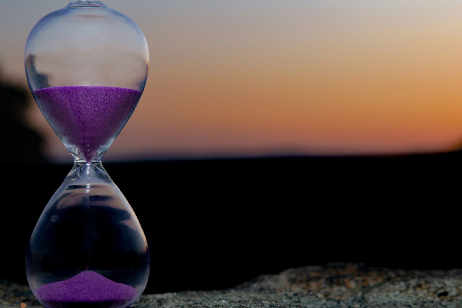 Person standing on cliff at sunset — patience and perspective in sales